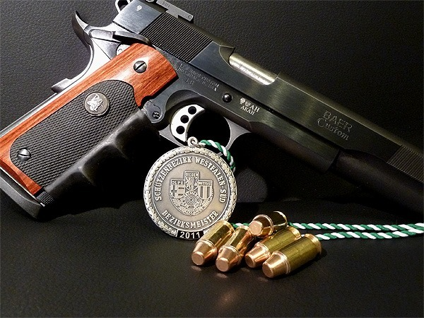 Symbolbild: Großkaliberpistole mit Munition und Medaille